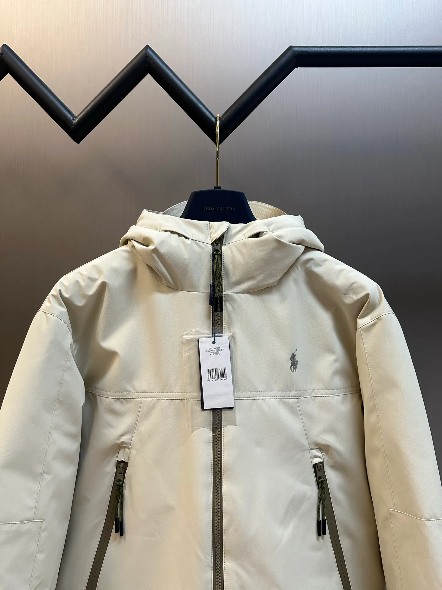 P970 Ralph Lauren logo hooded down jacket. The density of high-density nylon taffeta is about 210T-300T. The surface is smooth and slightly matte. It has excellent windproof and waterproof performance (with DWR water-repellent treatment). It has strong wrinkle resistance and is easy to care for. It is in line with the positioning of American casual "durable and practical".  The inner lining is made of 100% polyamide. The high-density and tight weaving process prevents fine lint from getting out of the gaps in the fabric. The smooth surface improves the putting on and taking off experience, and the excellent wear and tear resistance ensures damage caused by frequent use, while the light and soft texture does not affect the overall weight.  It uses 90 white duck down with a weight of 220g to ensure excellent thermal insulation performance. After strict screening and processing, the velvet is not easily drilled, ensuring durability. The classic jacket has a slightly loose fit, with slightly dropped shoulder lines (the shoulder width is 1-2cm wider than the standard fit). The length reaches the hips, and the sleeves are slightly tapered straight sleeves, taking into account freedom of movement and casual style.  The adjustable Velcro on the cuffs allows you to freely adjust the tightness according to the thickness of your wrist and personal preferences, effectively preventing cold wind from intruding, and improving the warmth performance. Two zippered pockets on the front are convenient for placing frequently used items, and the zipper design ensures that items are not easily lost. A built-in pocket on the left side of the chest provides a safe storage space for some small private items.  The drawstring design at the hem allows you to adjust the shape of the jacket according to your body shape and dressing needs. Whether it is loose and casual or slim and neat, you can easily control it.  Polo horse logo on the left chest: flat satin stitch embroidery (satin embroidery), using 100% polyester high color fastness embroidery thread (the color number is consistent with the brand's standard red color card), the stitch density is 12-15 stitches/cm, the outline of the horse logo is clear, and the details of the rider and horse are burr-free. Precise positioning through the template (12cm from the bottom of the collar and 8cm from the placket) ensures symmetry and centering.  size：s m l xl
